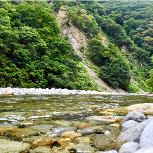 Olfattology - Hotan klarer Fluss mit Kieselsteinen und dichtem Grün an steilem Berghang im Kunlun-Gebirge