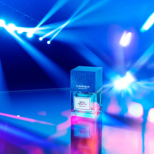 Carner Barcelona - Dream Collection - Ibiza Nights Parfumflakon mit blauem Holzdeckel vor buntem Lichtspiel