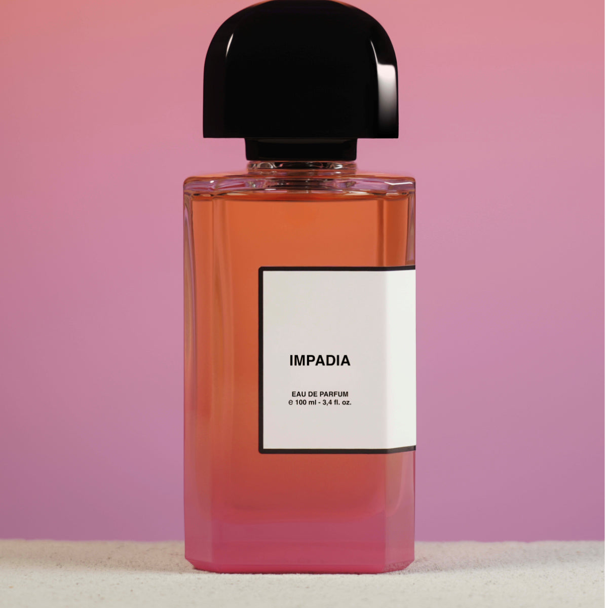 bdk Parfums-  Impadia Parfumflakon mit fließendem Farbverlauf von Orange zu Rosa vor zartem Hintergrund