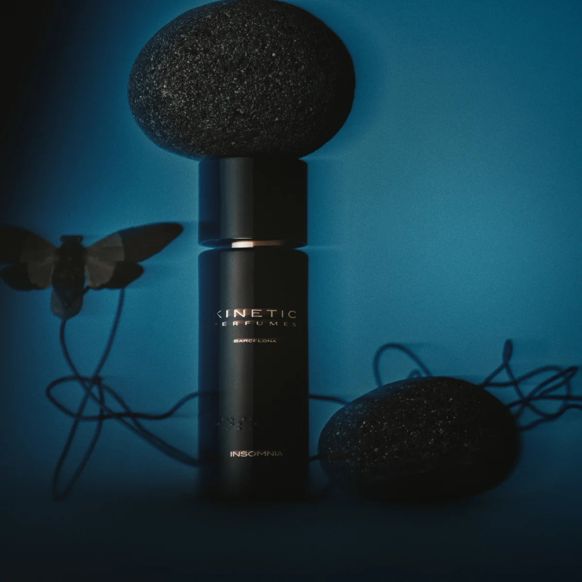 Kinetic Perfumes - Insomnia Parfum in schwarzem Flakon mit goldener Schrift und dekorativen Steinen auf blauem Hintergrund