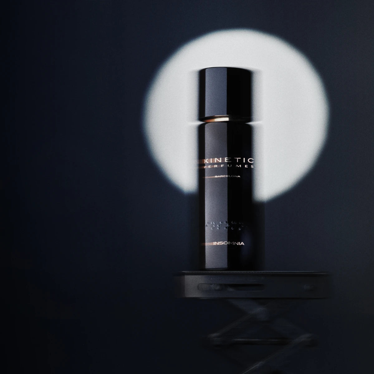 Kinetic Perfumes - Insomnia Parfumflakon in glänzendem Schwarz mit goldenem Schriftzug vor dunklem Hintergrund und Lichtkreis