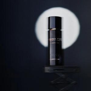 Kinetic Perfumes - Insomnia Parfumflakon in glänzendem Schwarz mit goldenem Schriftzug vor dunklem Hintergrund und Lichtkreis