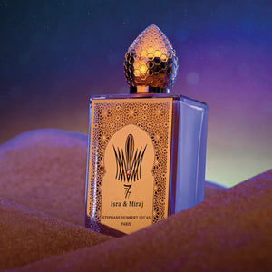 Stéphane Humbert Lucas 777 - Isra & Miraj Parfumflakon mit goldener Verzierung auf sandigem Untergrund vor dunklem Hintergrund
