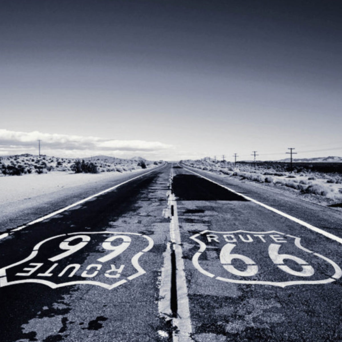 Xerjoff - Join The Club - Ivory Route zeigt weite Straße mit Route 66 Markierung in karger Landschaft bei klarem Himmel