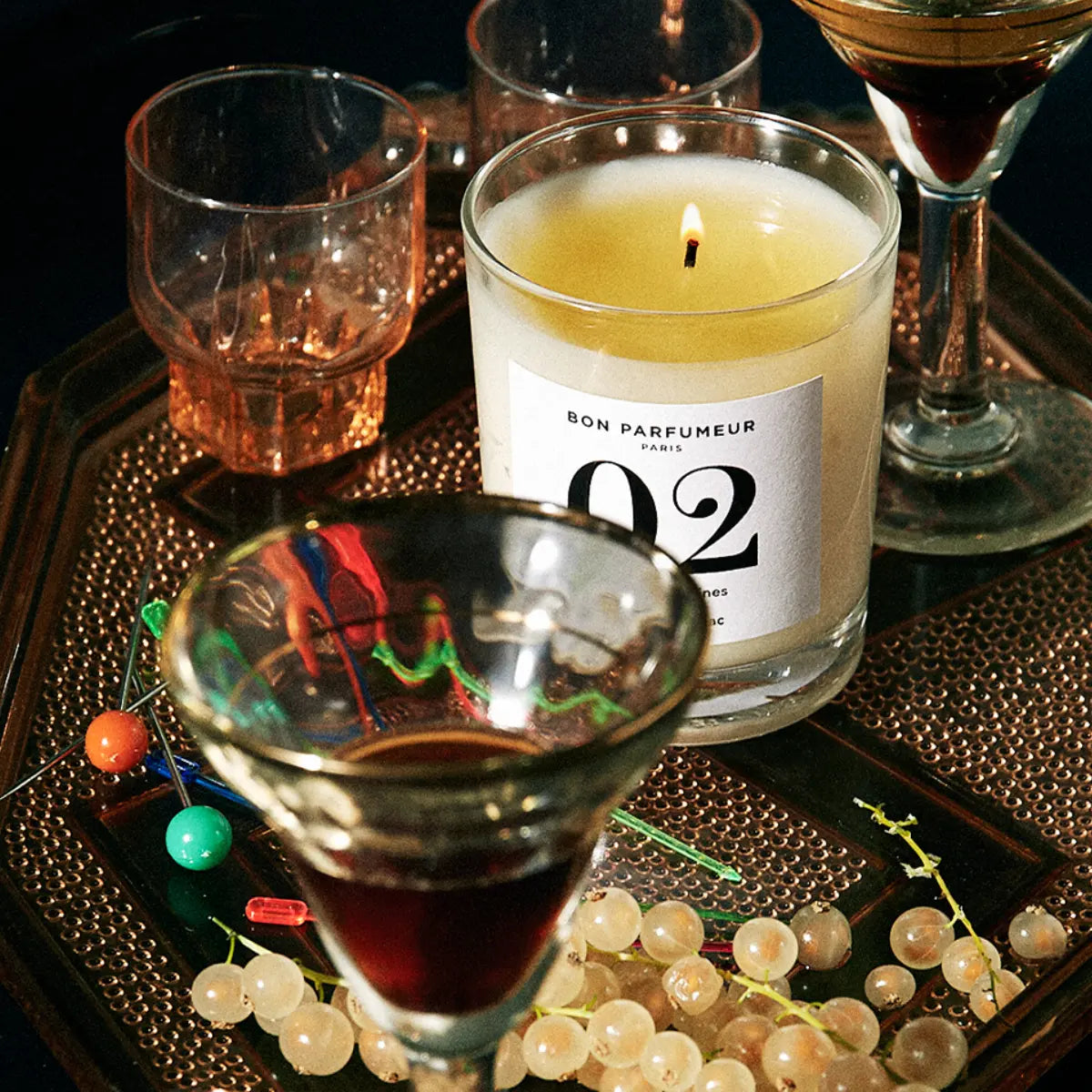 Bon Parfumeur - Candle 02 brennende Kerze im klaren Glas auf Tablett mit Gläsern und weißen Trauben arrangiert