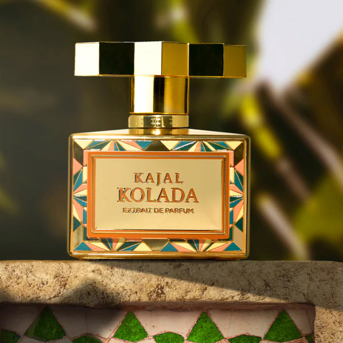 Kajal - Kolada Parfumflakon mit goldfarbenem Verschluss und buntem geometrischem Muster auf Natursteinfläche