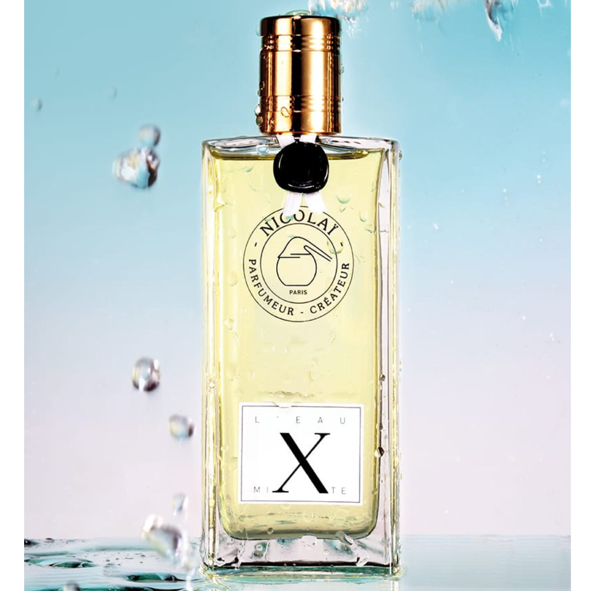 Nicolaï - L'Eau Mixte klarer Flakon mit goldfarbenem Verschluss und schwarzem Siegel vor spritzigem Wasserhintergrund