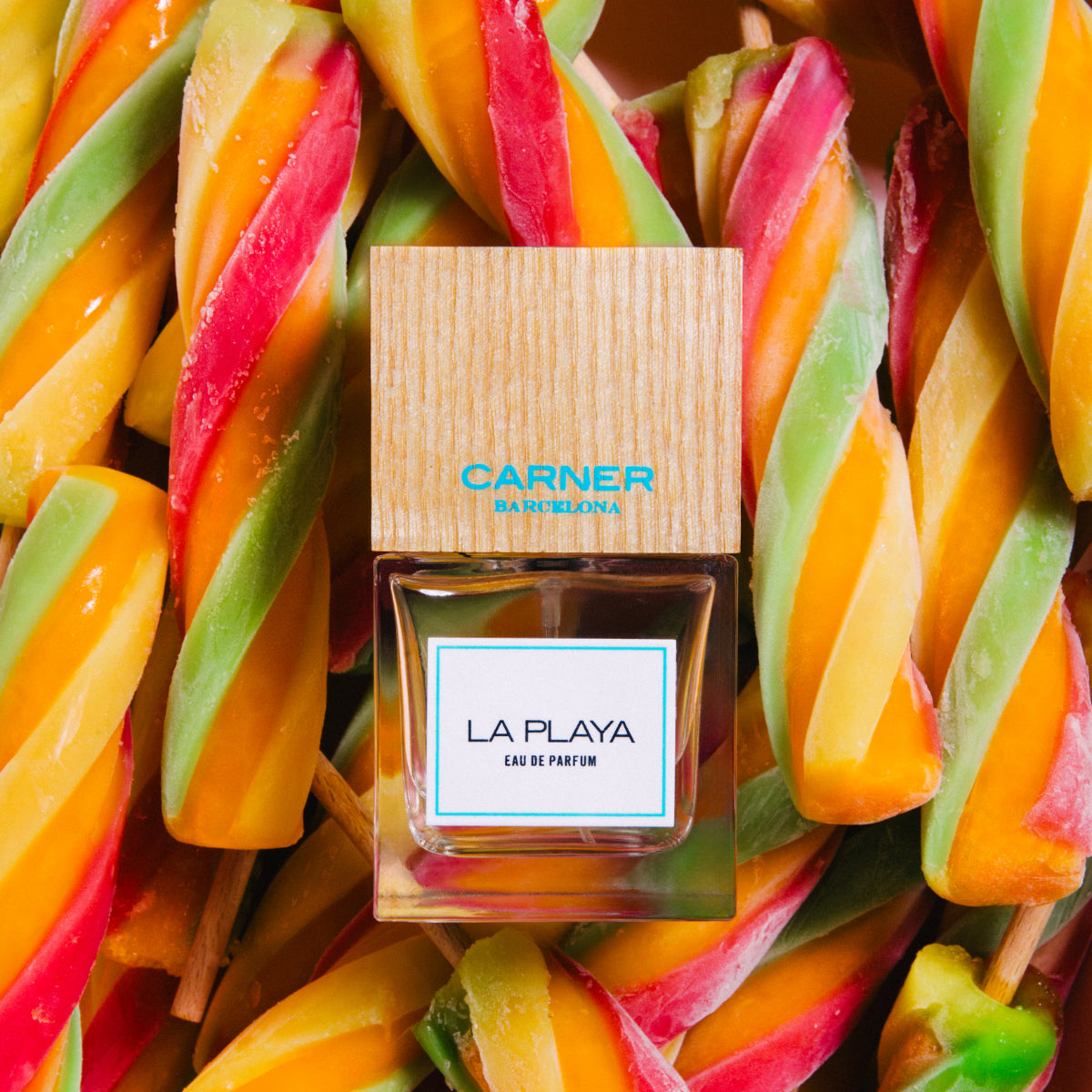 Carner Barcelona - Mediterranean Collection - La Playa Duftflakon mit Holzkappe vor bunten tropischen Zuckerstangen