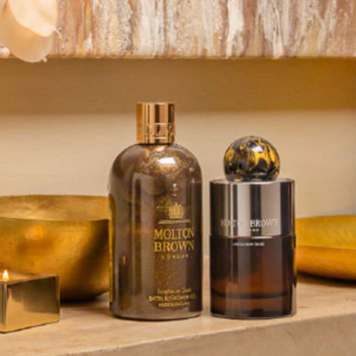 Molton Brown - Labdanum Dusk Flakon in dunklem Glas mit goldfarbenem Verschluss auf warmem Hintergrund
