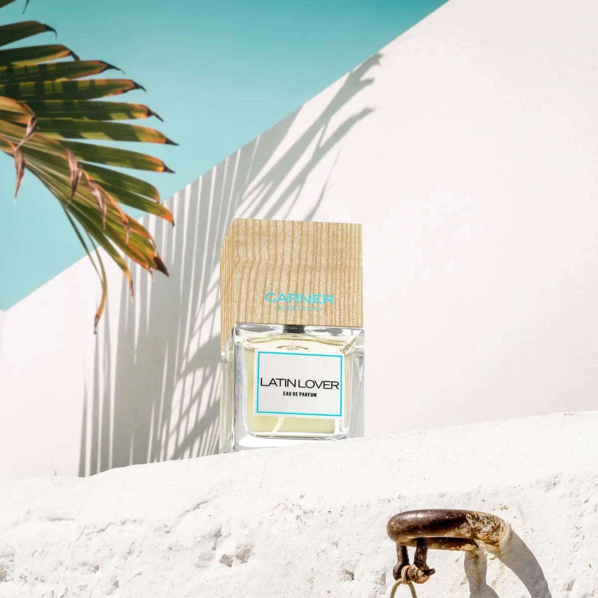 Carner Barcelona - Love Collection - Latin Lover Parfum mit Holzverschluss vor hellem Hintergrund und tropischem Blatt Schatten