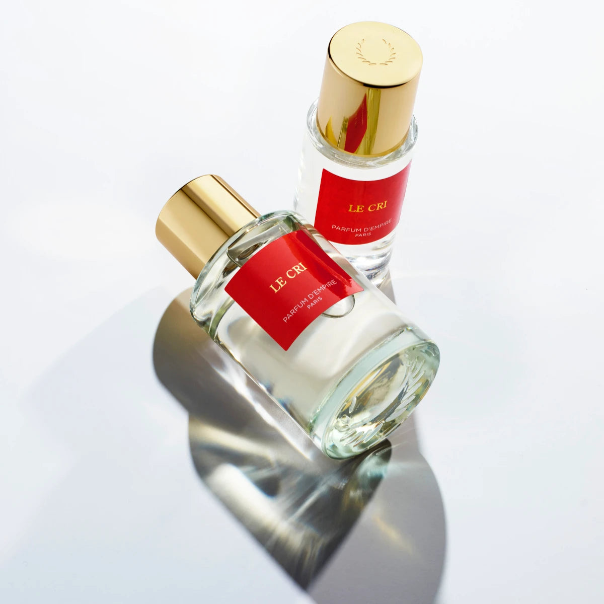 Parfum d'Empire - LE CRI de la lumière zwei klare Glasflakons mit goldenem Verschluss und rotem Etikett auf weißem Hintergrund