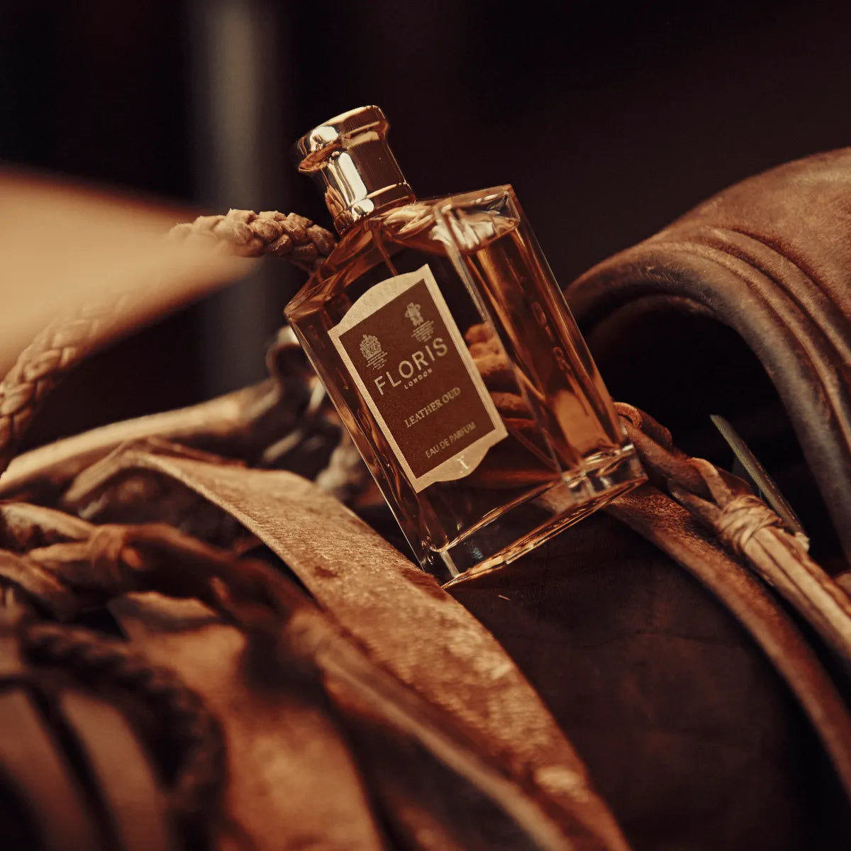 Floris - Leather Oud Parfümflakon mit bernsteinfarbenem Duft in elegantem Glas vor braunem Lederhintergrund