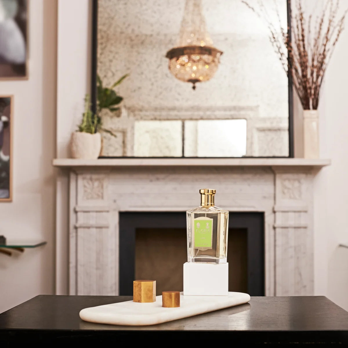 Floris - Limes Flakon mit goldfarbenem Verschluss und grünem Etikett auf elegantem weißen Podest vor Kamin