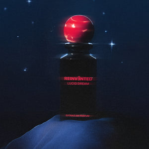 Reinvented Parfums - Lucid Dream Flakon mit schwarzem Glas und rotem, kugelförmigem Verschluss vor Nachtillumination