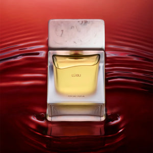 Sora Dora - White Collection - Lü Bu Parfumflakon mit bernsteinfarbener Flüssigkeit vor rotem, wellenförmigem Hintergrund