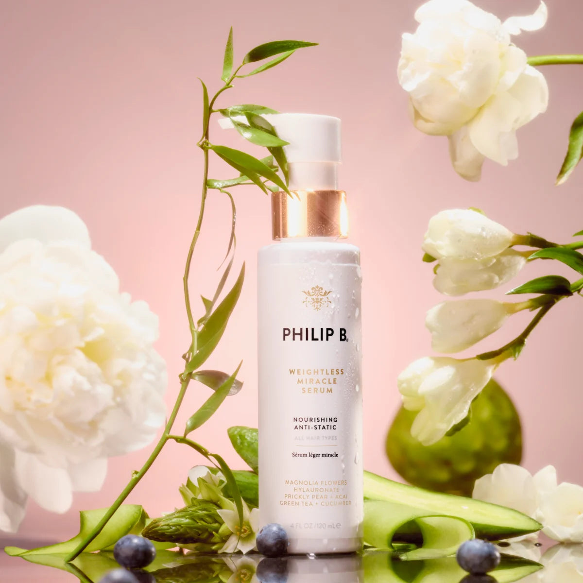 Philip B - Weightless Miracle Serum im eleganten Spender vor zarten weißen Blüten und grünem Laub auf rosafarbenem Hintergrund