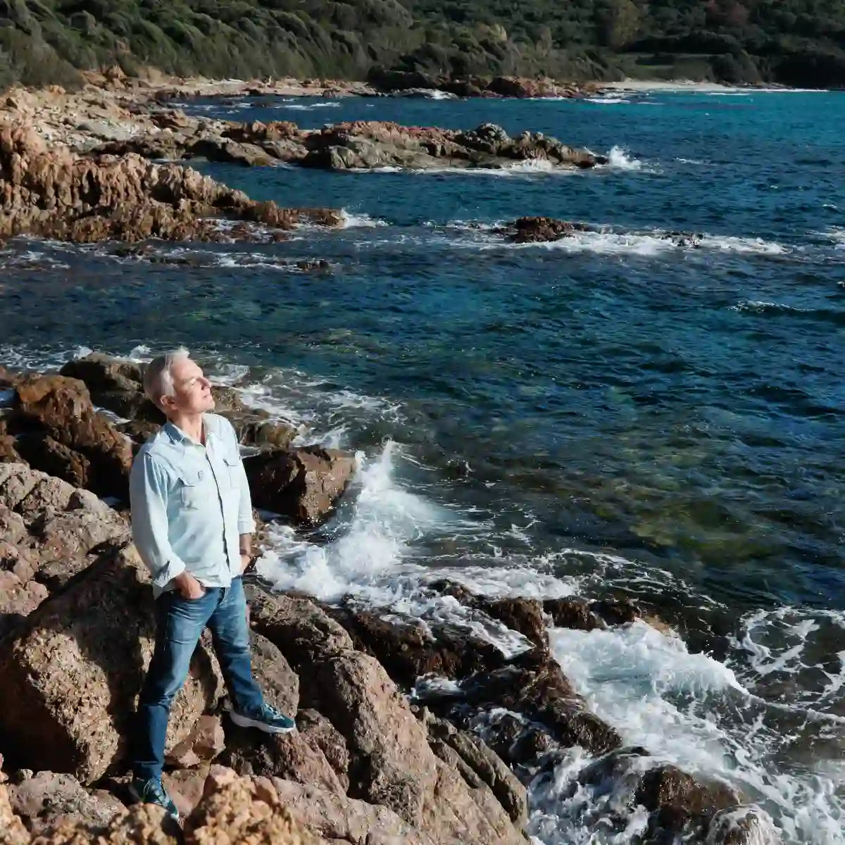 Parfum d'Empire - Iskander Entdecker steht an felsiger Küste mit Blick auf das lebendige blaue Meer