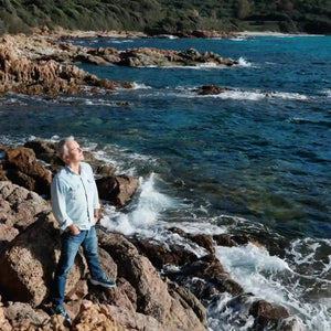 Parfum d'Empire - Iskander Entdecker steht an felsiger Küste mit Blick auf das lebendige blaue Meer
