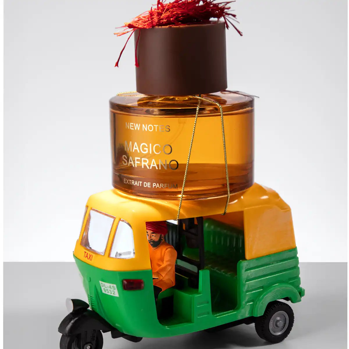 New Notes - Modern Liquid Collection - Magico Safrano Parfumflakon in bernsteinfarbener Flüssigkeit auf bunter Tuk-Tuk-Figur