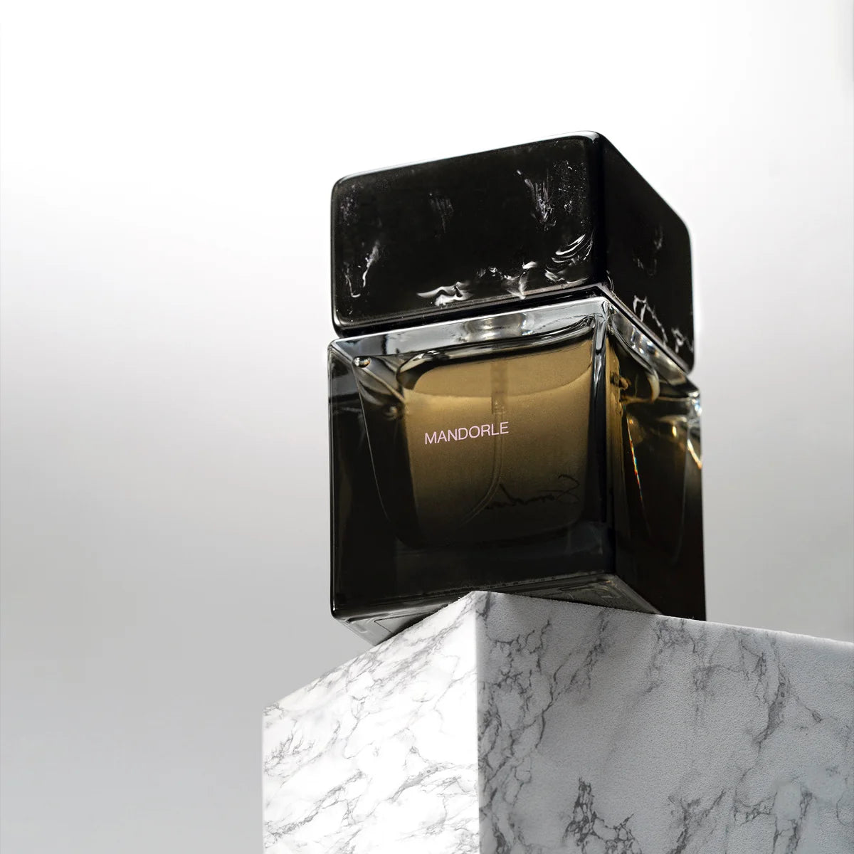 Sora Dora - Mandorle Parfumflakon mit dunklem Glas und markantem schwarzem Deckel auf Marmorstein präsentiert