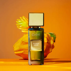 Gritti - Ivy Collection - Mango Aoud Parfumflakon mit goldfarbenem Verschluss vor warmem orangefarbenem Hintergrund