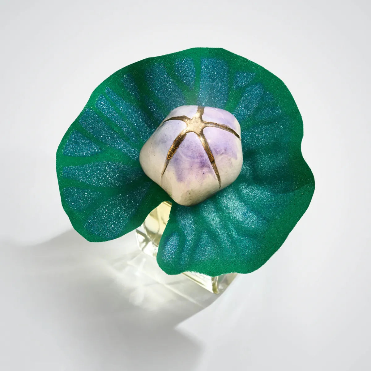 Mendittorosa - Talismans Collection - Mauna zeigt Flakon mit grünem Blatt und zart violett-goldenem Deckel in künstlerischem Design