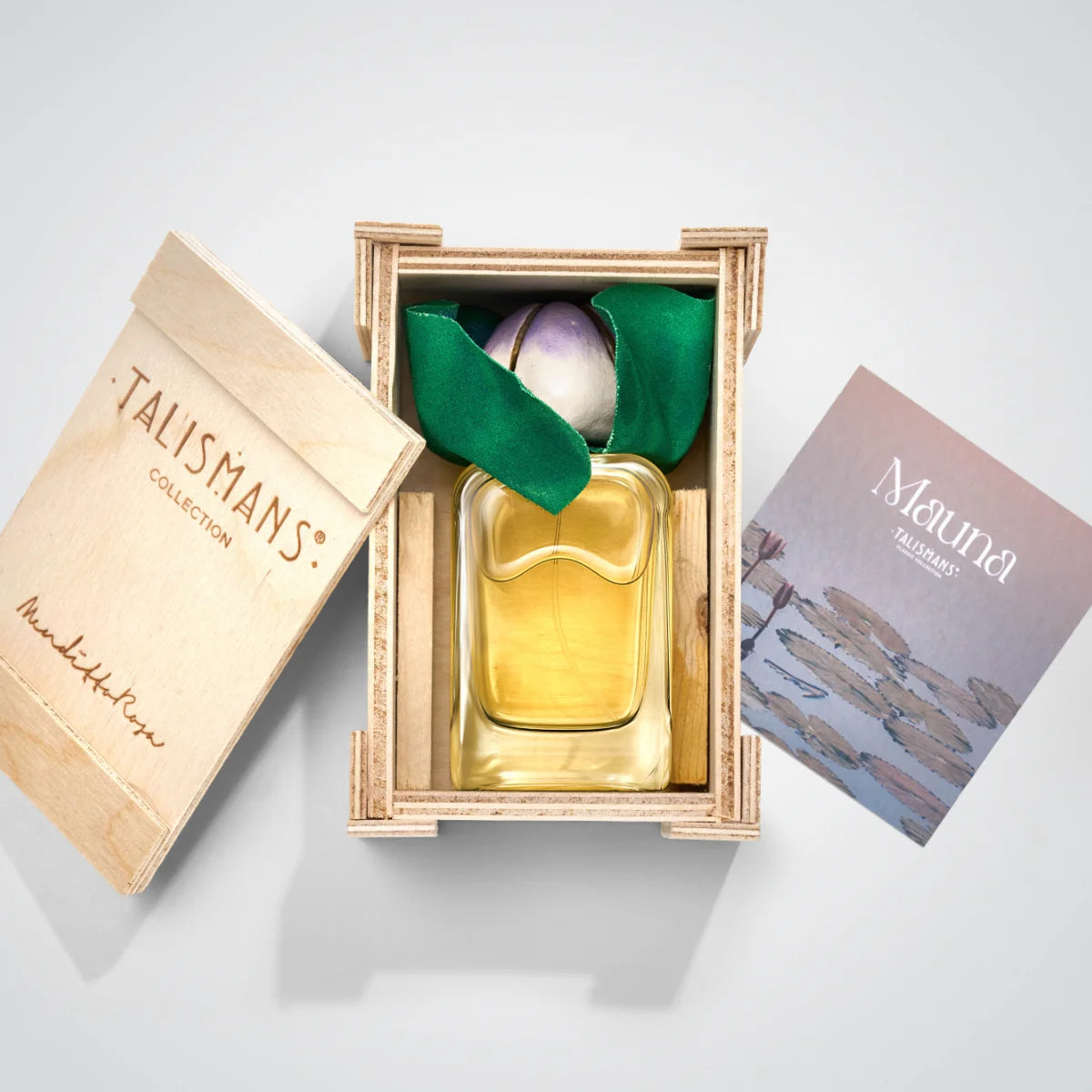 Mendittorosa - Talismans Collection - Mauna zeigt Flakon mit gelber Flüssigkeit und dekorativer violetter Blüte in Holzkiste