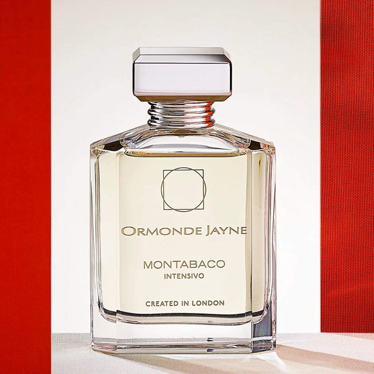 Ormonde Jayne - Montabaco Intensivo Parfümflakon mit klarem Glas und markantem silbernem Verschluss vor hell-rotem Hintergrund
