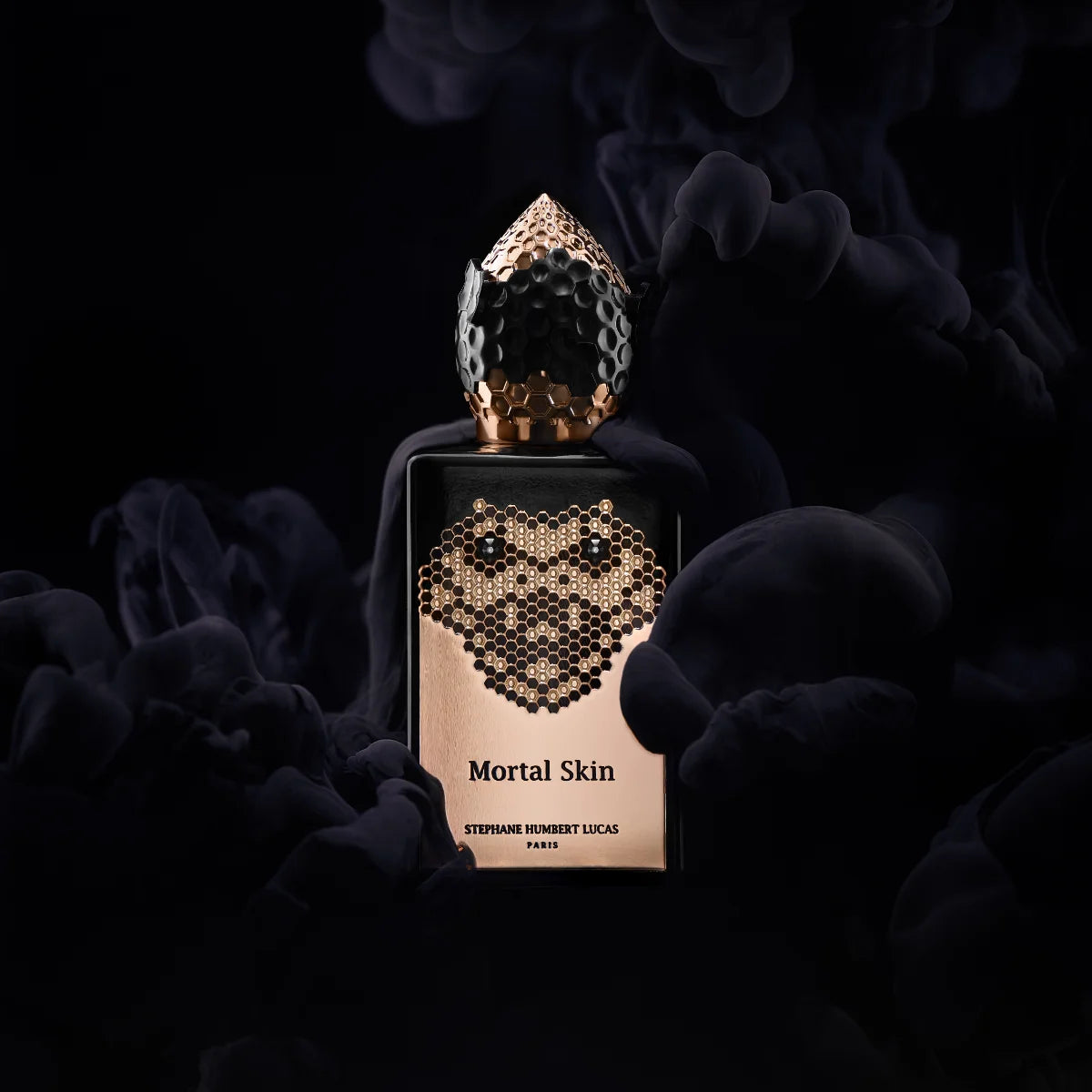 Stéphane Humbert Lucas 777 - Mortal Skin Parfumflakon mit schwarzem Gehäuse und goldener Schlangengravur vor dunklem Rauchhintergrund