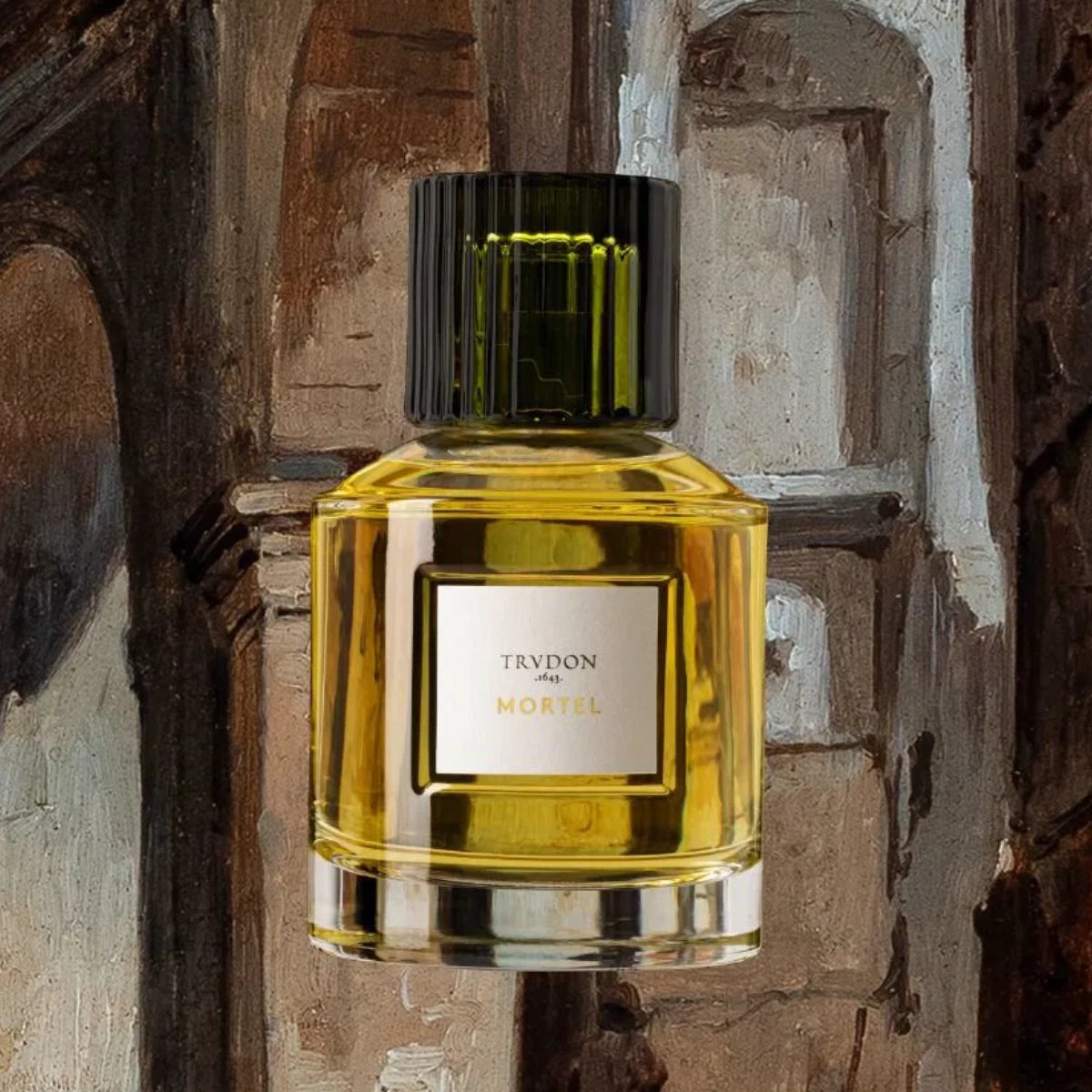Trudon - Mortel Parfumflakon mit schwarzem Verschluss und goldgelber Flüssigkeit vor rustikalem Hintergrund