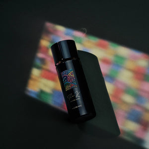 Kinetic Perfumes - Mosaic zeigt schwarzen Flakon mit farbigem Mosaikmotiv vor dunklem Hintergrund mit Lichtspiel