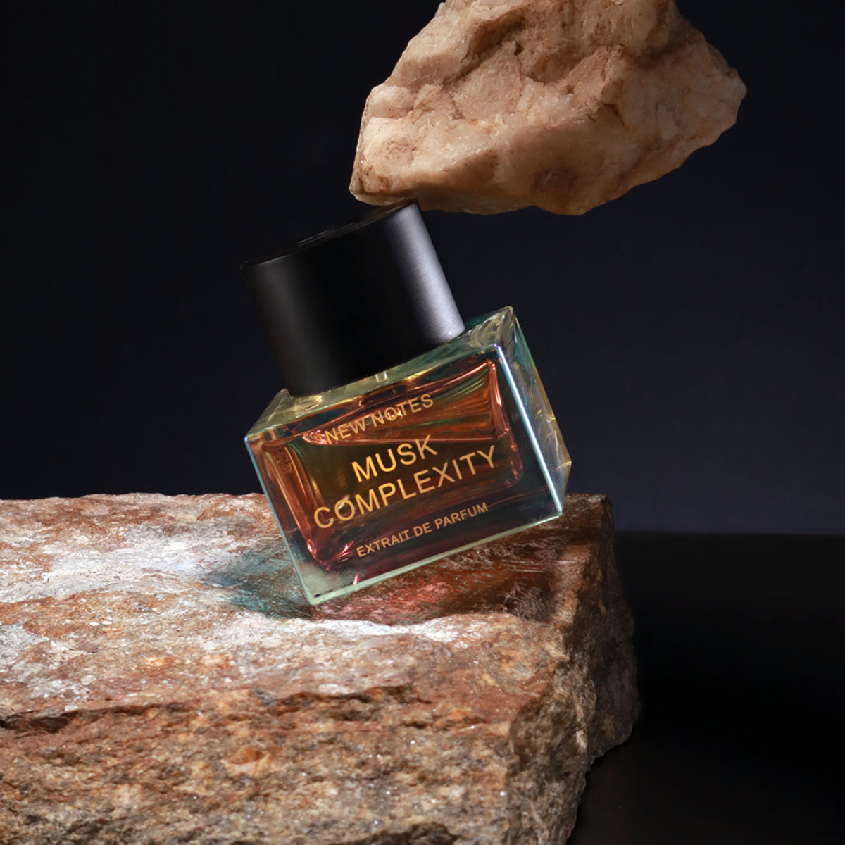 New Notes - Hologram Collection - Musk Complexity Parfumflakon auf rauem Stein mit dunklem Hintergrund