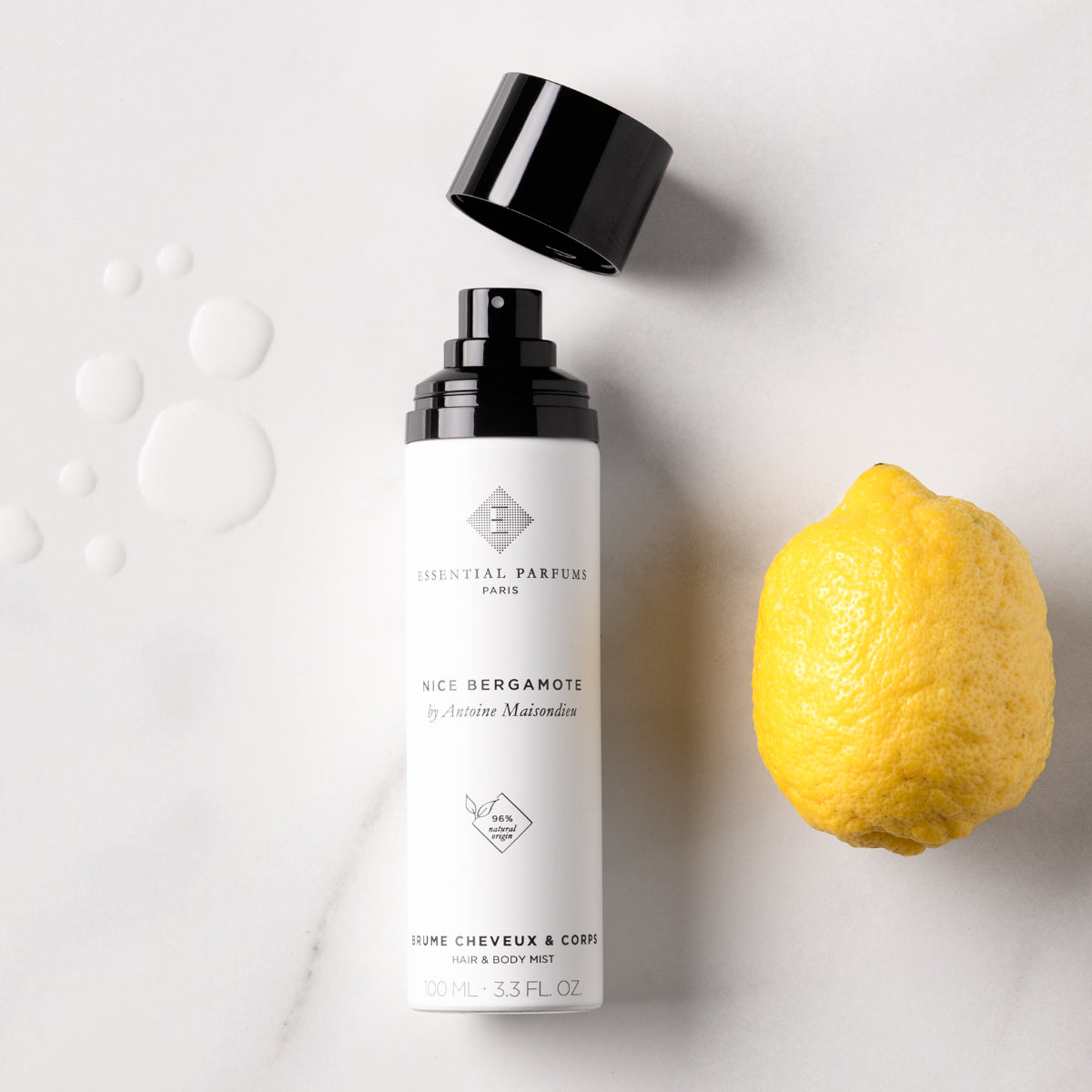 Essential Parfums - Nice Bergamote - Hair & Body Mist Flakon mit schwarzem Sprühkopf und natürlicher Bergamotte auf hellem Untergrund