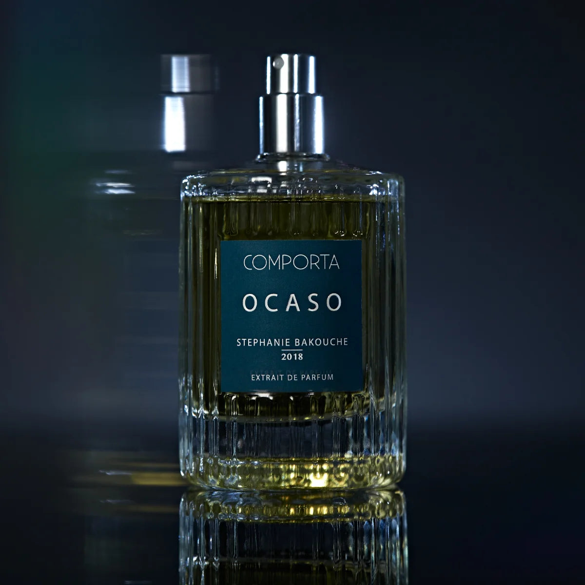 Comporta Perfumes - Ocaso Parfumflakon mit klar strukturiertem Glas und tiefblauem Etikett vor dunklem Hintergrund