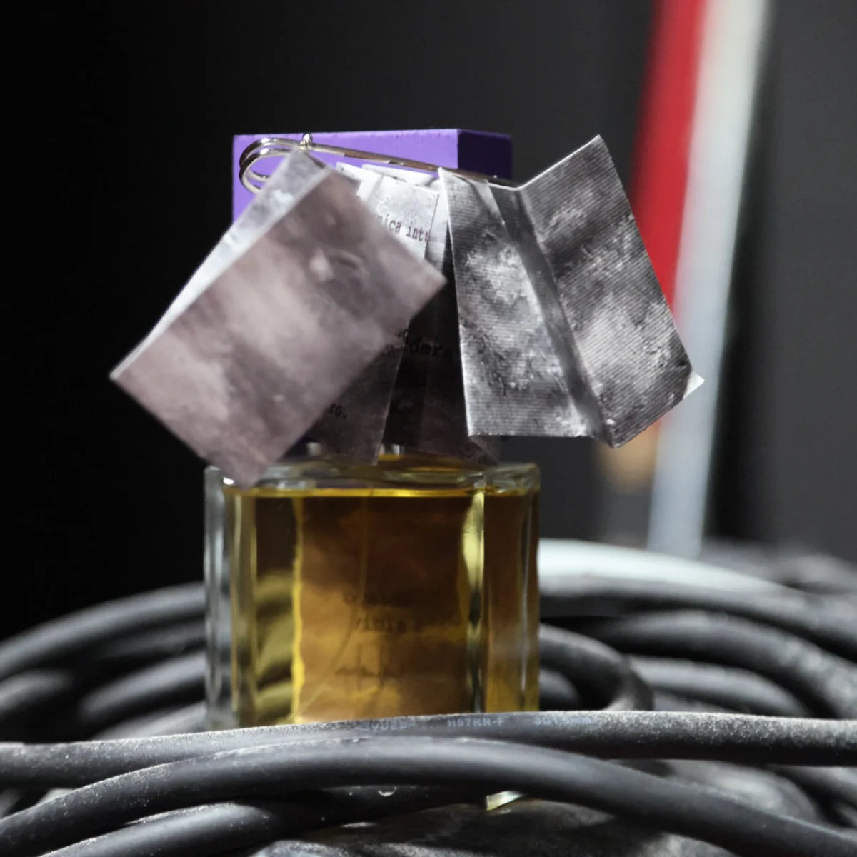 Filippo Sorcinelli - Unum - Oceano Viola zeigt Flakon mit violettem Deckel und kunstvollem Anhänger vor dunklem Hintergrund