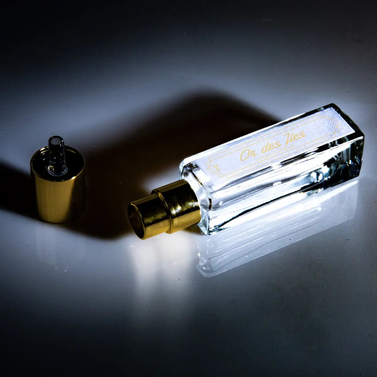 Cherigan - Or des Iles rechteckiger Parfumflakon mit goldenem Zerstäuber und abgenommener Kappe auf edlem, dunklem Hintergrund