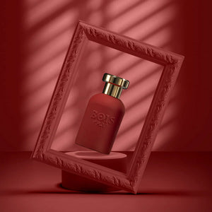 Bois 1920 - Oro Collection - Oro Rosso roter Flakon mit goldfarbenem Verschluss im dekorativen Rahmen vor rotem Hintergrund