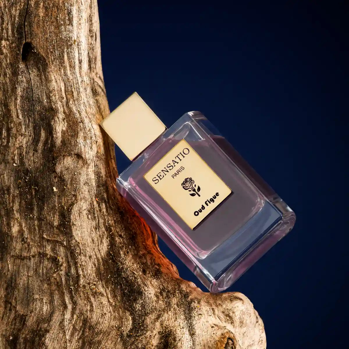 Sensatio Paris - Oud Figue Parfumflakon mit hellem Verschluss auf naturbelassenem Holz vor tiefblauem Hintergrund