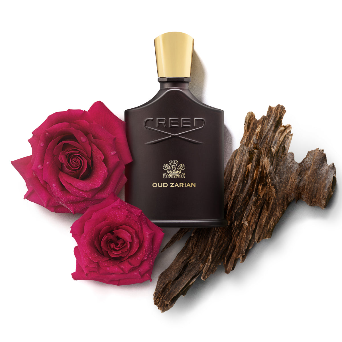 Creed - Oud Zarian Parfumflakon in dunklem Glas mit goldfarbenem Verschluss, umgeben von Rosen und Oud-Holz auf weißem Hintergrund
