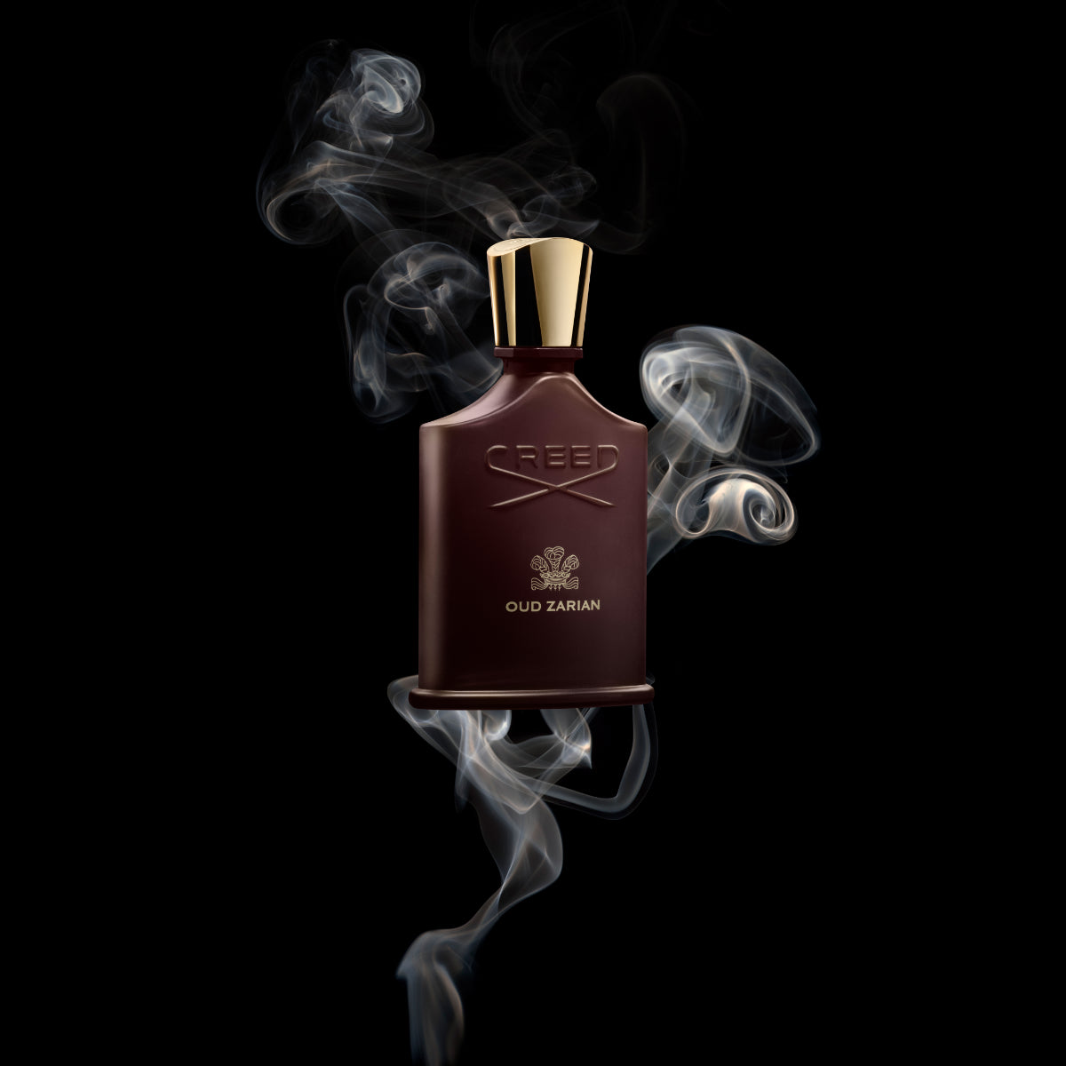 Creed - Oud Zarian Parfumflakon in dunkelbraunem Glas mit goldfarbenem Verschluss und Rauch auf schwarzem Hintergrund