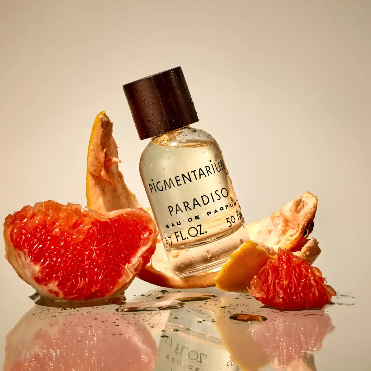 Pigmentarium - Paradiso zeigt Parfümflakon mit hellem Duftöl und dunklem Holzverschluss neben aufgeschnittener Grapefruit