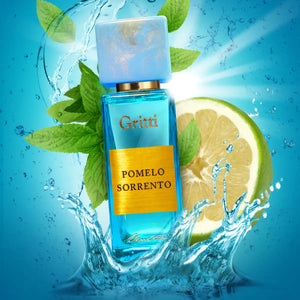 Gritti - Smaragd Collection - Pomelo Sorrento Parfumflakon in leuchtendem Blau mit goldfarbenem Etikett vor Grapefruit und spritzendem Wasser