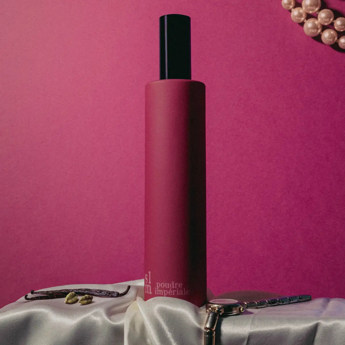 Sous Le Manteau - Poudre Impériale eleganter Flakon vor pinkem Hintergrund mit eleganten Accessoires