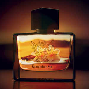 Jovoy - Remember Me Parfumflakon mit warmem Bernsteinlicht, verschnörkeltem Emblem und schwarzem Verschluss vor dunklem Hintergrund