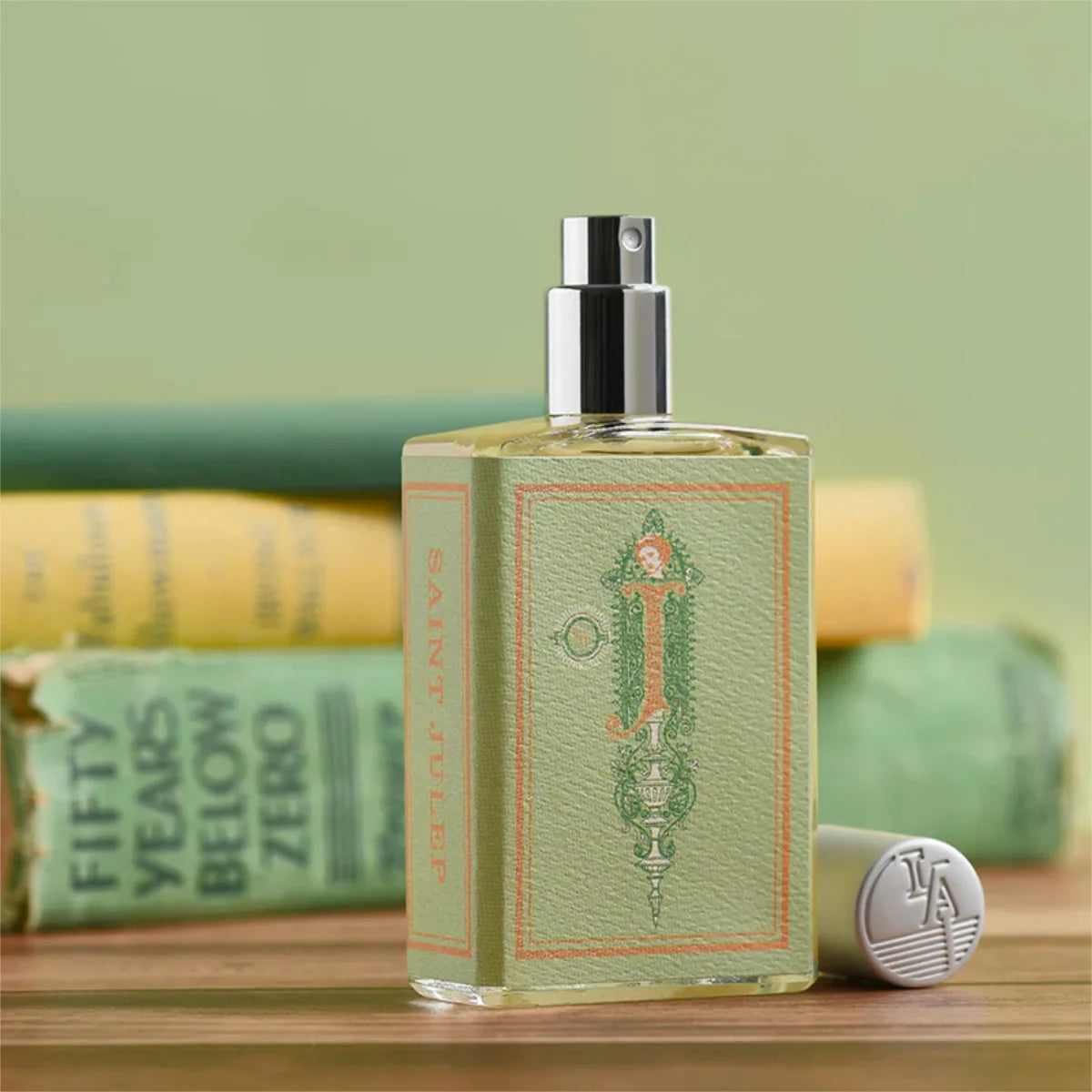 Imaginary Authors - Saint Julep Parfumspray mit grünem Etikett und silbernem Zerstäuber vor gestapelten Büchern