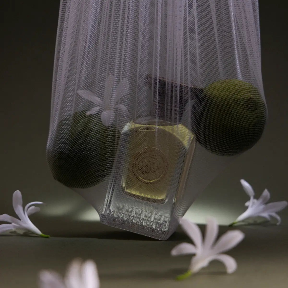 Anfas - Essence of Arabia Collection - Salam Duftflakon mit bernsteinfarbener Flüssigkeit in Netz mit grünen Früchten und weißen Blüten