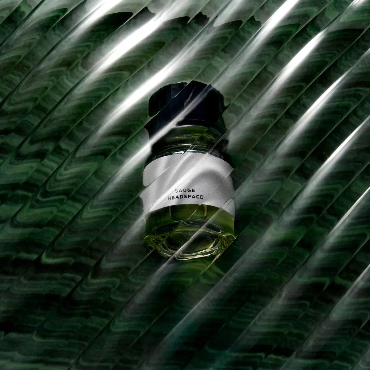 Headspace - Sauge Parfumflakon mit grünem Inhalt und minimalistischem Etikett vor dunklem, strukturiertem Hintergrund