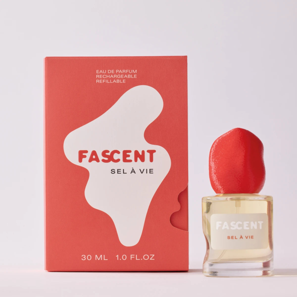Fascent - Sel à Vie Parfumflakon mit organisch geformtem, rotem Deckel neben roter Verpackung auf hellem Hintergrund