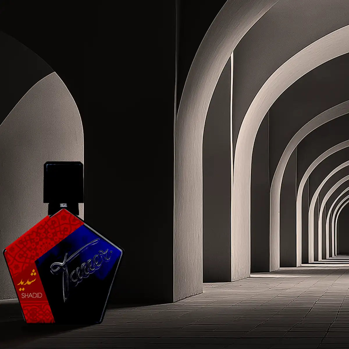 Andy Tauer - Shadid Parfumflakon mit markantem rot-blauem Design vor architektonischen Bögen in Schwarz-Weiß