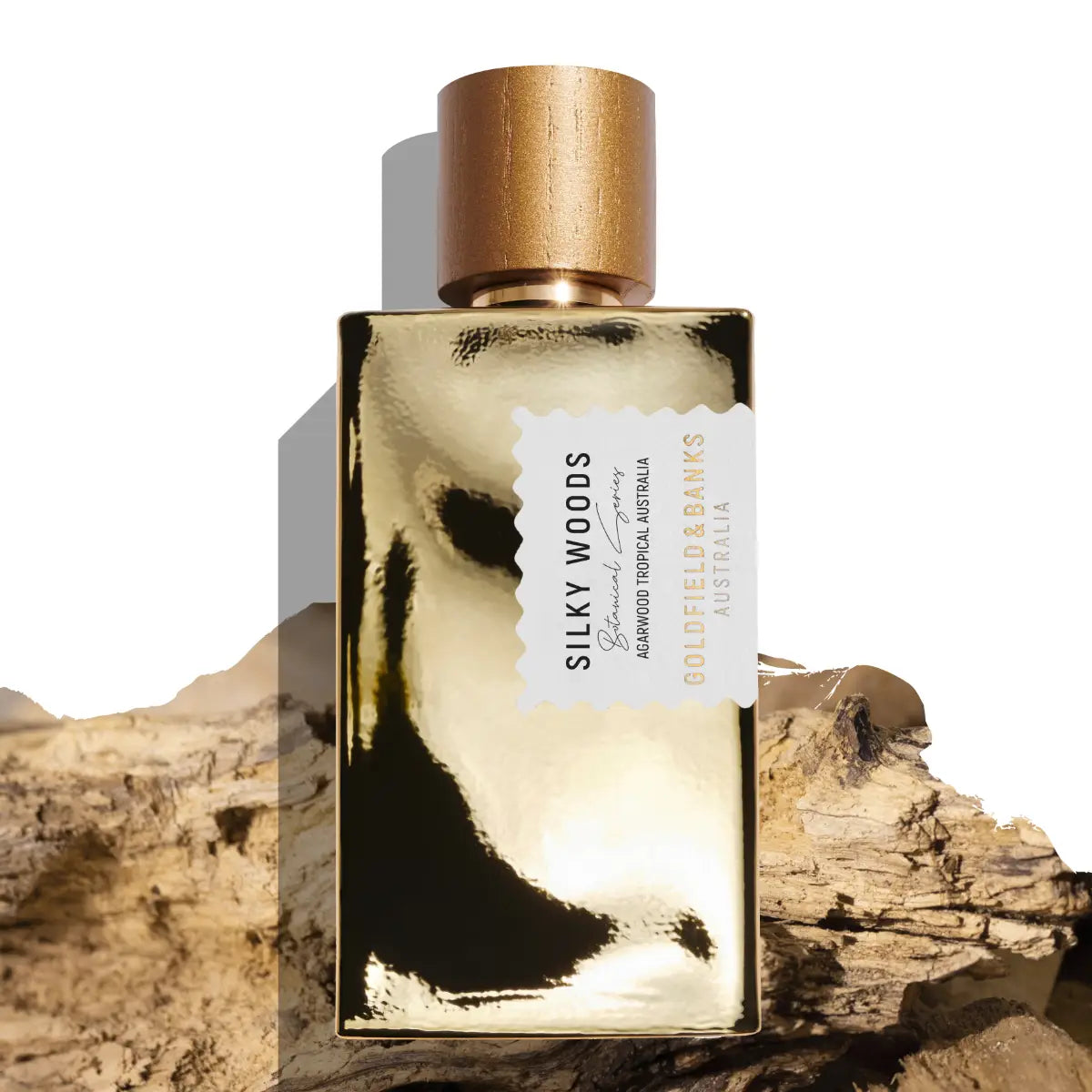 Goldfield & Banks - Botanical Series - Silky Woods Parfumflakon in glänzendem goldfarbenem Design mit braunem Holzverschluss auf Holzstücken